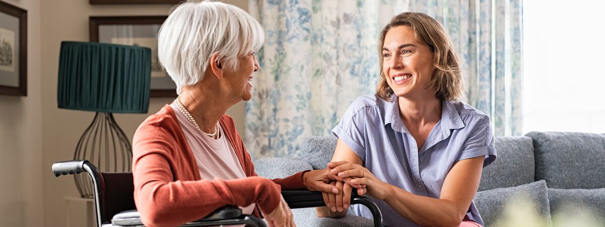 Older woman in a wheelchair holding hands with another woman