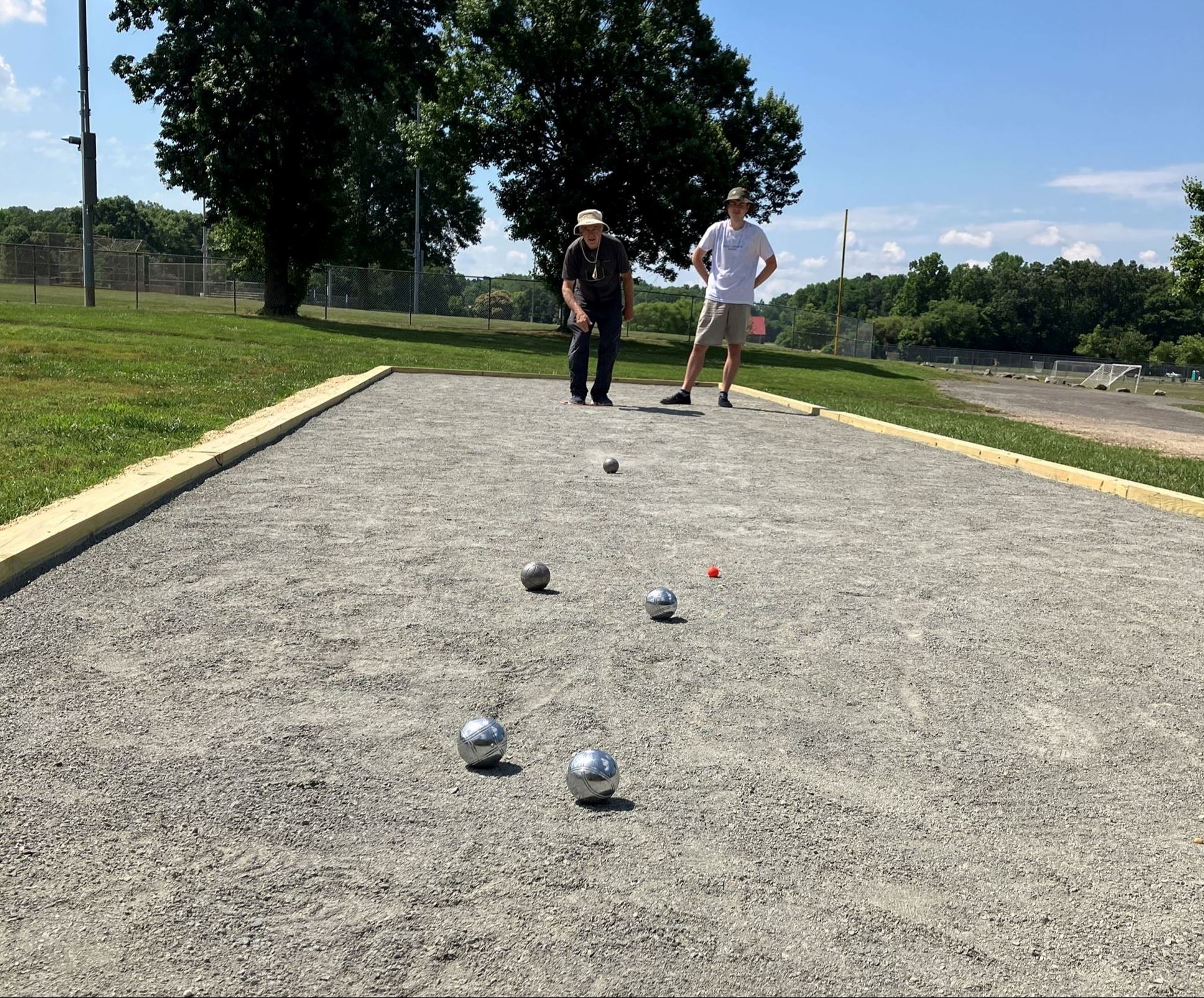 Players throw boules on a petanque court